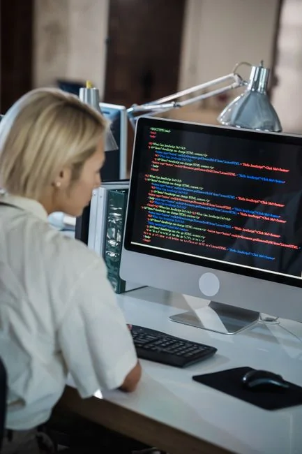 Person browsing the web on a MacBook at a wooden desk with a smartphone.